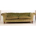 An early 20th century chesterfield sofa upholstered in a olive green button back fabric on turned