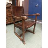 An early 20th century oak framed open arm chair upholstered in brown leather