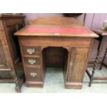 An early 20th century oak desk, the sloping lift up lid over three drawers and cupboard door