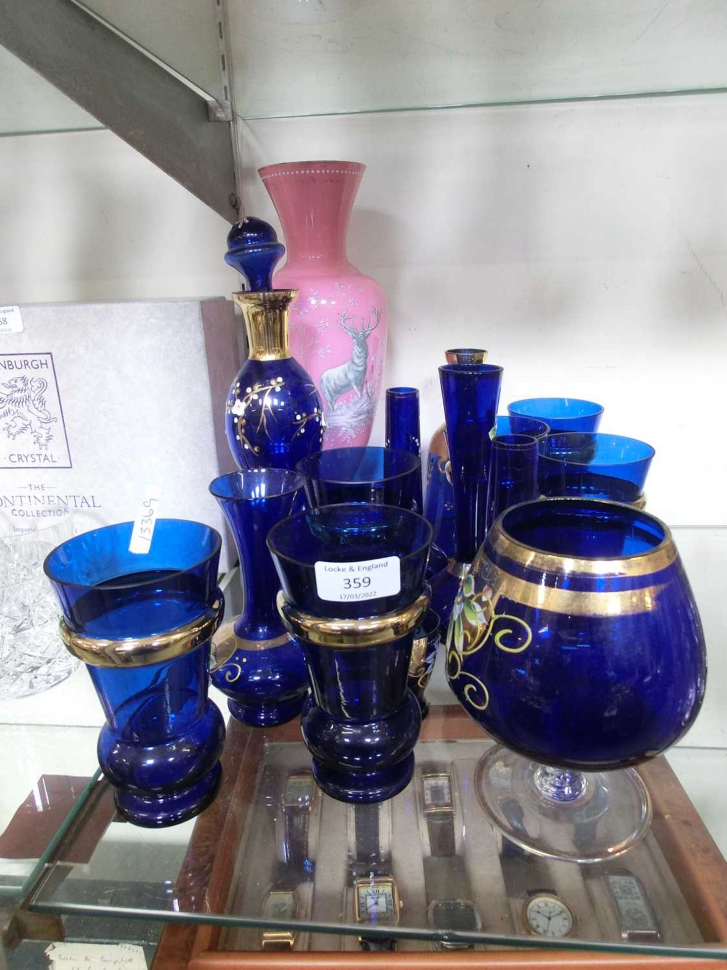 A selection of blue glass with gold rimmed edging together with a pink glass vase with stag design