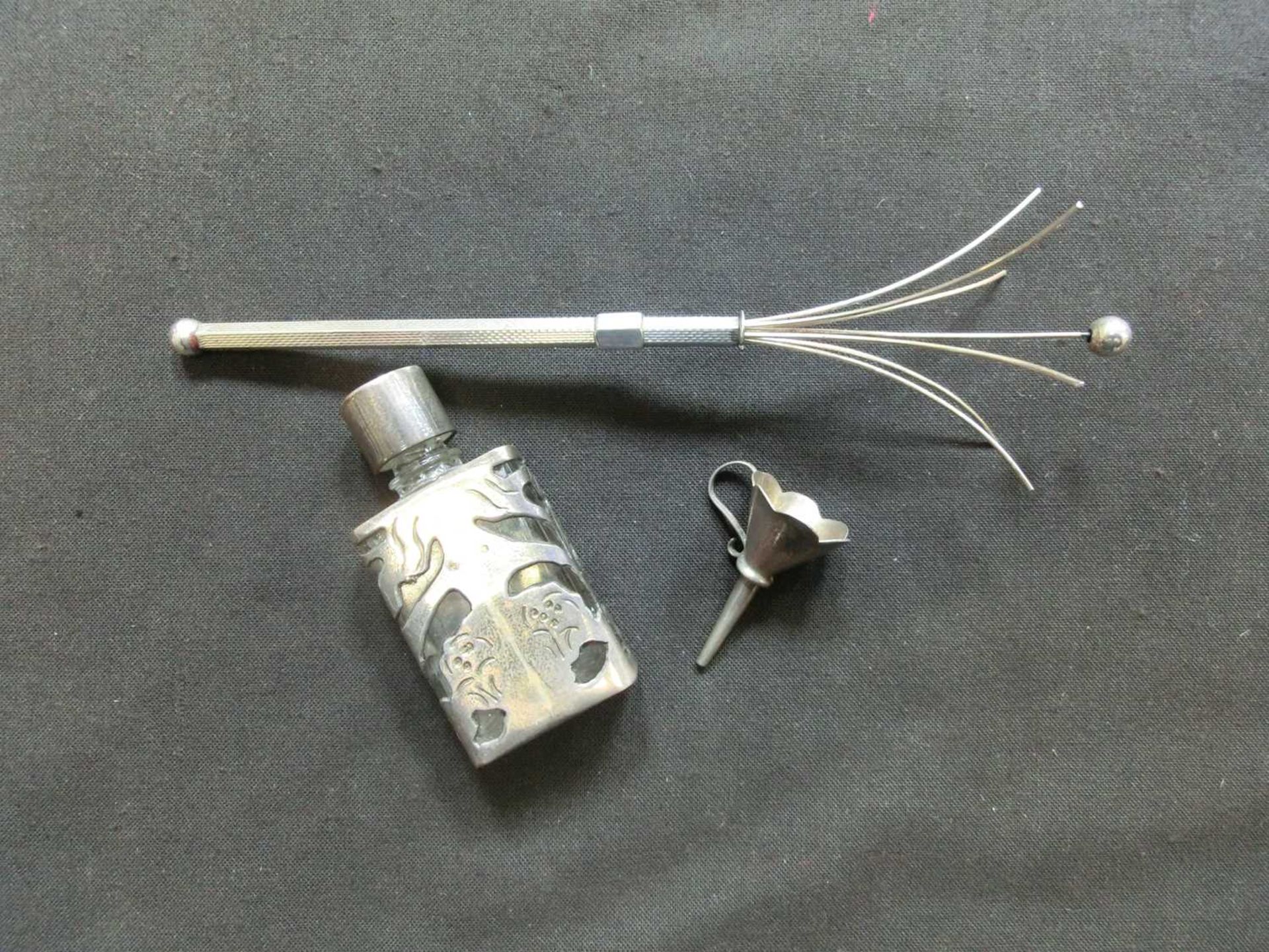 A small whisk stamped 'Sterling' together with a small white metal funnel and a white metal