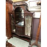 An Edwardian mahogany glazed cabinet having open storage flanked by glazed doors with carving to