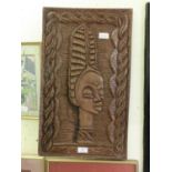 A carved wooden panel depicting an African lady's head