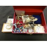 A red jewellery box containing an assortment of costume jewellery