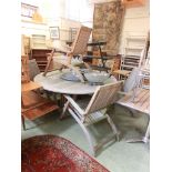 A weather teak circular garden table with a grey marble lazy Susan to center together with a set