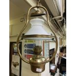 A hanging brass oil lantern with white glass shade