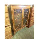 A modern yew veneered glazed two door cabinet