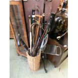 A wicker basket containing an assortment of walking sticks, shooting stick, etc