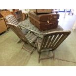 A weathered teak garden table along with a set of three matching chairs