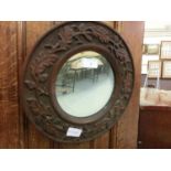 A circular carved oak bevel glass wall mirror