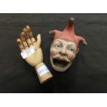 A ceramic jester's head together with a wooden hand