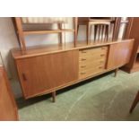 A mid-20th century teak sideboard, the sliding cupboard doors flanking four drawersCosmetic knocks