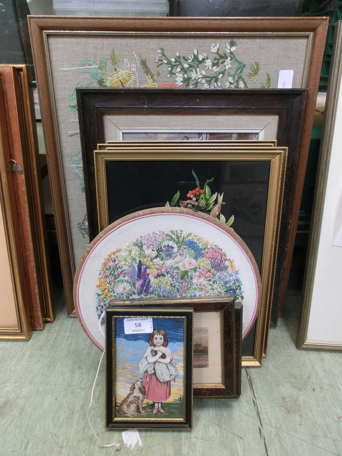 A collection of framed and unframed artworks, mainly needleworks