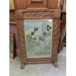 An early 20th century carved oak framed fire screen with embroidered panel