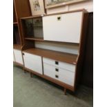 A 1980s laminated teak effect dresser having a pair of smoked glass doors with pull down flap