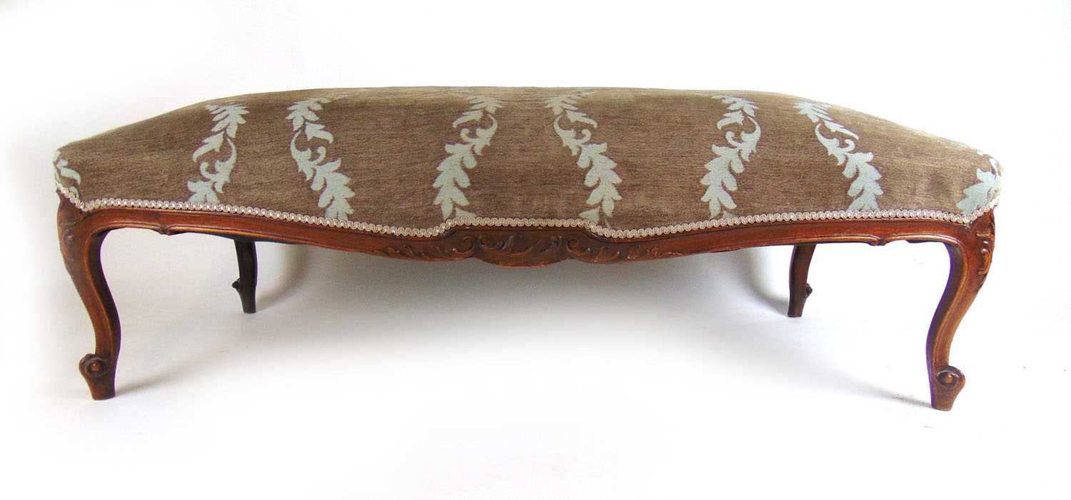 A 19th century French walnut stool of trapezium form upholstered in a floral patterned fabric the