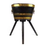 An 18th century oak and brass banded wine cooler on later base, the oval body with brass lion mask