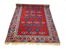 A handwoven Turkish rug, the triple line border surrounding the red ground field with serrated