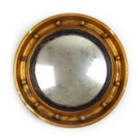 A Regency gilt wood convex mirror. the moulded frame with spheres surrounding the circular plate,