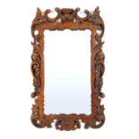 A 19th century Rococo carved pine mirror, the frame surmounted with a nest over swags, garlands