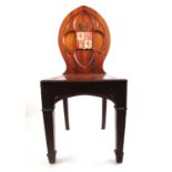 An early 19th century mahogany Gothic hall chair, the carved quatrefoil back with armorial shield