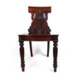 An early 19th century mahogany hall chair in the style of Gillows, the carved back over the banded