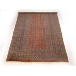 A handwoven Afghan rug, the multi line border surrounding the peach ground field with two columns of