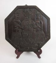 A 20th century Benin carved octagonal wooden plaque depicting three figures, w. 31 cm