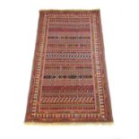 A handwoven Persian (?) rug, the multi line border surrounding the striped field, 214 cm x 128 cm