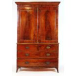 An early 19th century mahogany linen press, the cornice over two flame mahogany doors enclosing