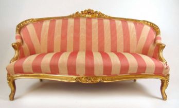 A 19th century carved giltwood settee upholstered in a striped pink fabric, the floral top rail