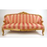 A 19th century carved giltwood settee upholstered in a striped pink fabric, the floral top rail