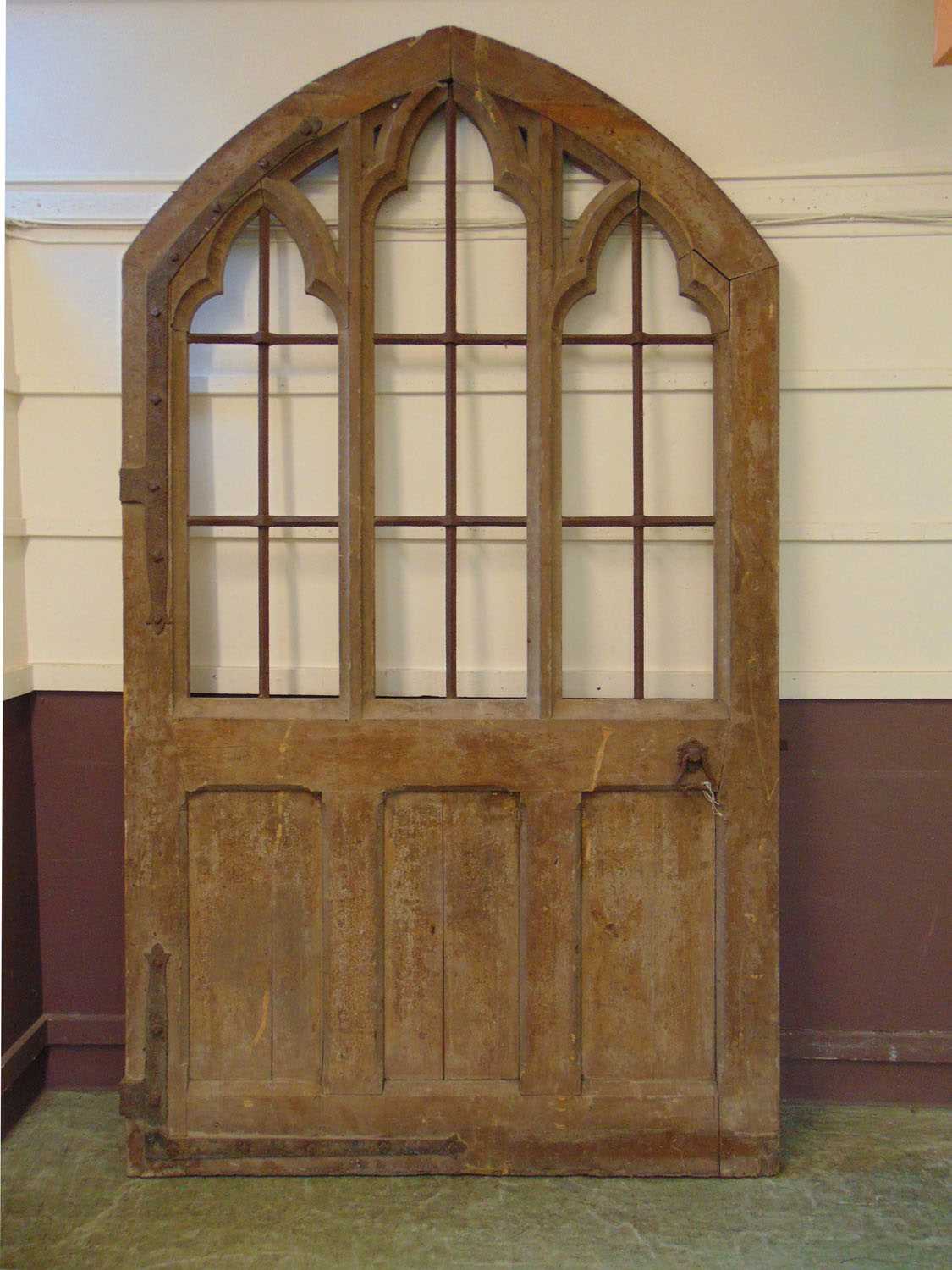 A 19th century scumbled pine Gothic door, the three apertures with cast iron lattice work over the