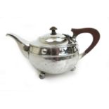 A George V silver arts and crafts design tea pot with embossed roundels and planished finish.