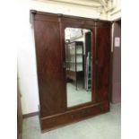 An early 20th century mahogany and amboyna banded three door wardrobe, the bevelled plate flanked by