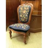 A Victorian walnut framed nursing chair with floral needlework upholstery on turned, carved, and