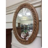 A carved pine floral framed oval mirror