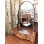 An early 19th century mahogany and strung toilet mirror, the oval plate over serpentine base with