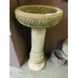 A composite stone bird bath on fluted and floral column