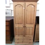 A modern pine two door wardrobe with two drawers to base