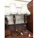 A pair of early 20th century turned mahogany table lamps with reeded middle sections