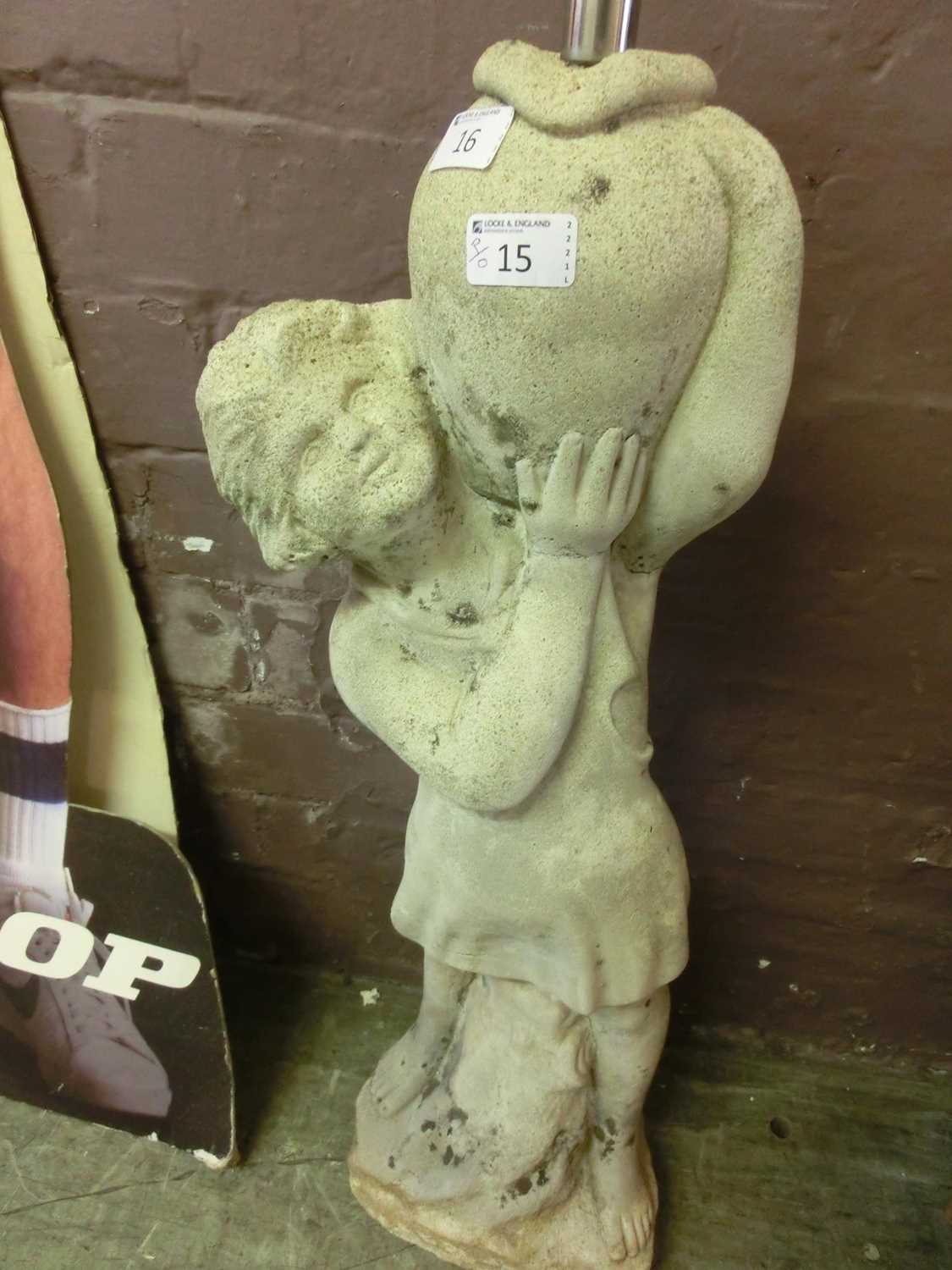 A composite stone garden water feature in the form of young boy holding an urn