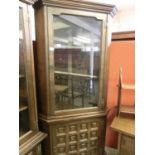 A Spanish oak full height corner cabinet having glazed door to top, the base having panelled door