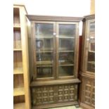 A Spanish oak glazed cabinet having a pair of glazed doors above panel doors