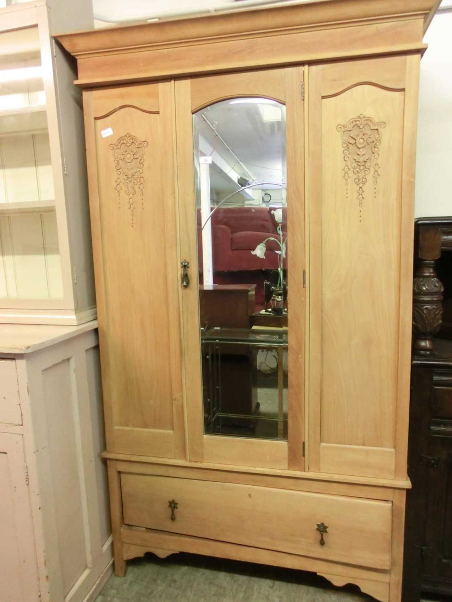 An early 20th century satinwood wardrobe having a bevel glass centre door with drawer to base