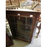 A wall mounted corner cabinet having a leaded glazed door