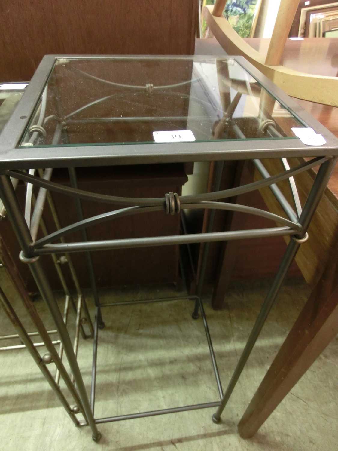 A modern square glass topped table with metal base