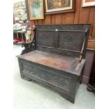 A Victorian carved oak bench, the arms with lion head terminals on the seat with storage under (A/