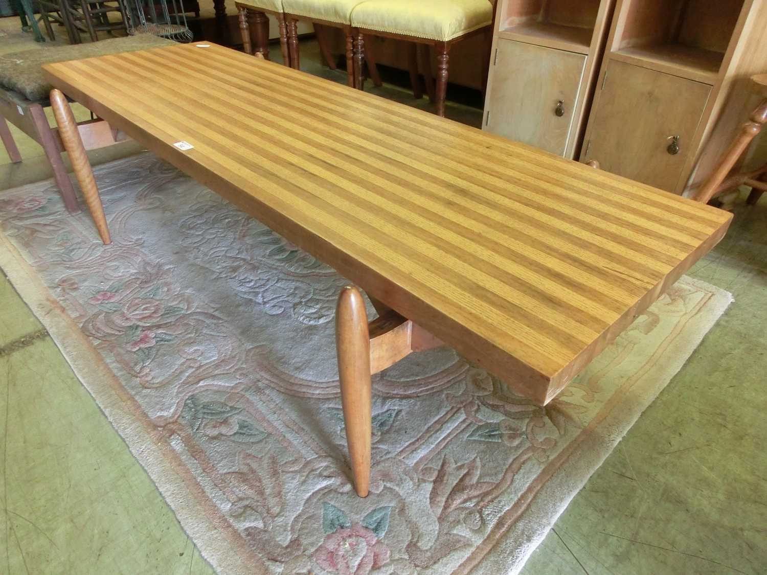 A mid-20th century coffee table, the top with contrasting woods on turned legsSome screws on legs