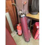 A red canvas golf bag with a selection of golf clubs